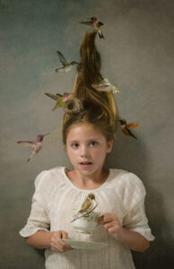 Nanci Hellmuth photograph A Touch of Magic of a girl holding a tea cup with birds flying around her with her hair standing up.